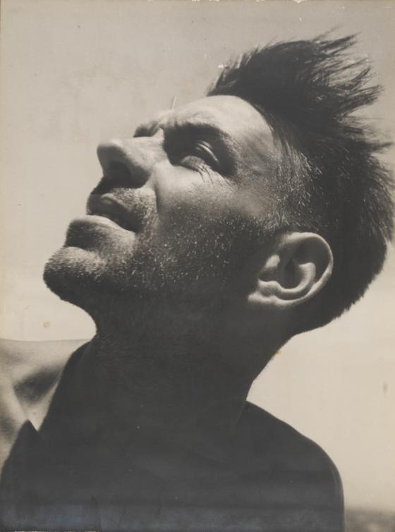 A sepia photographic portrait of a man tilting his face up to the sun. 