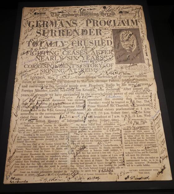 Cover of a discolour Sydney Morning Herald declaring the German surrender and covered in signatures.