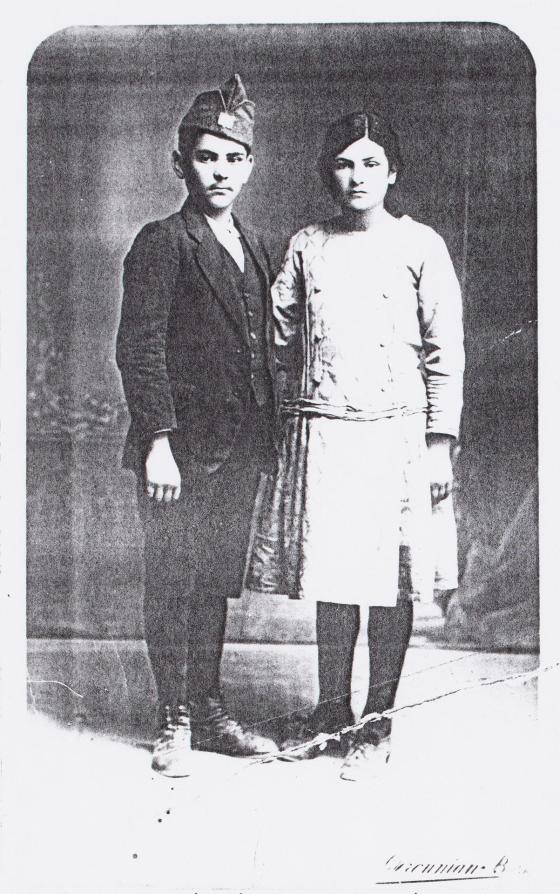 A young teenage boy and girl stand together.