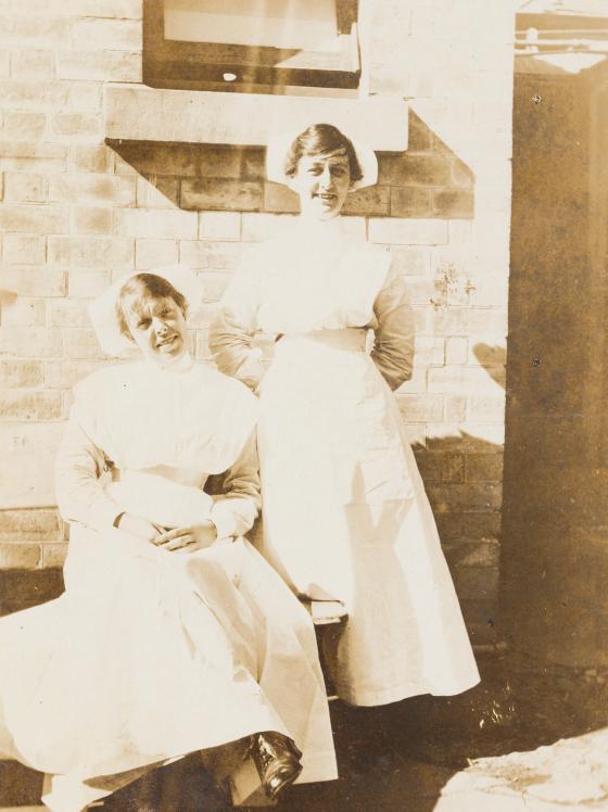 A sepia photograph depicting two women in nurse uniform, smiling.