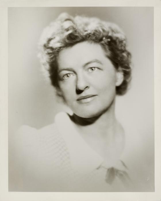 Aged looking black and white photographic portrait of a woman wearing a white blouse with rounded collar. 
