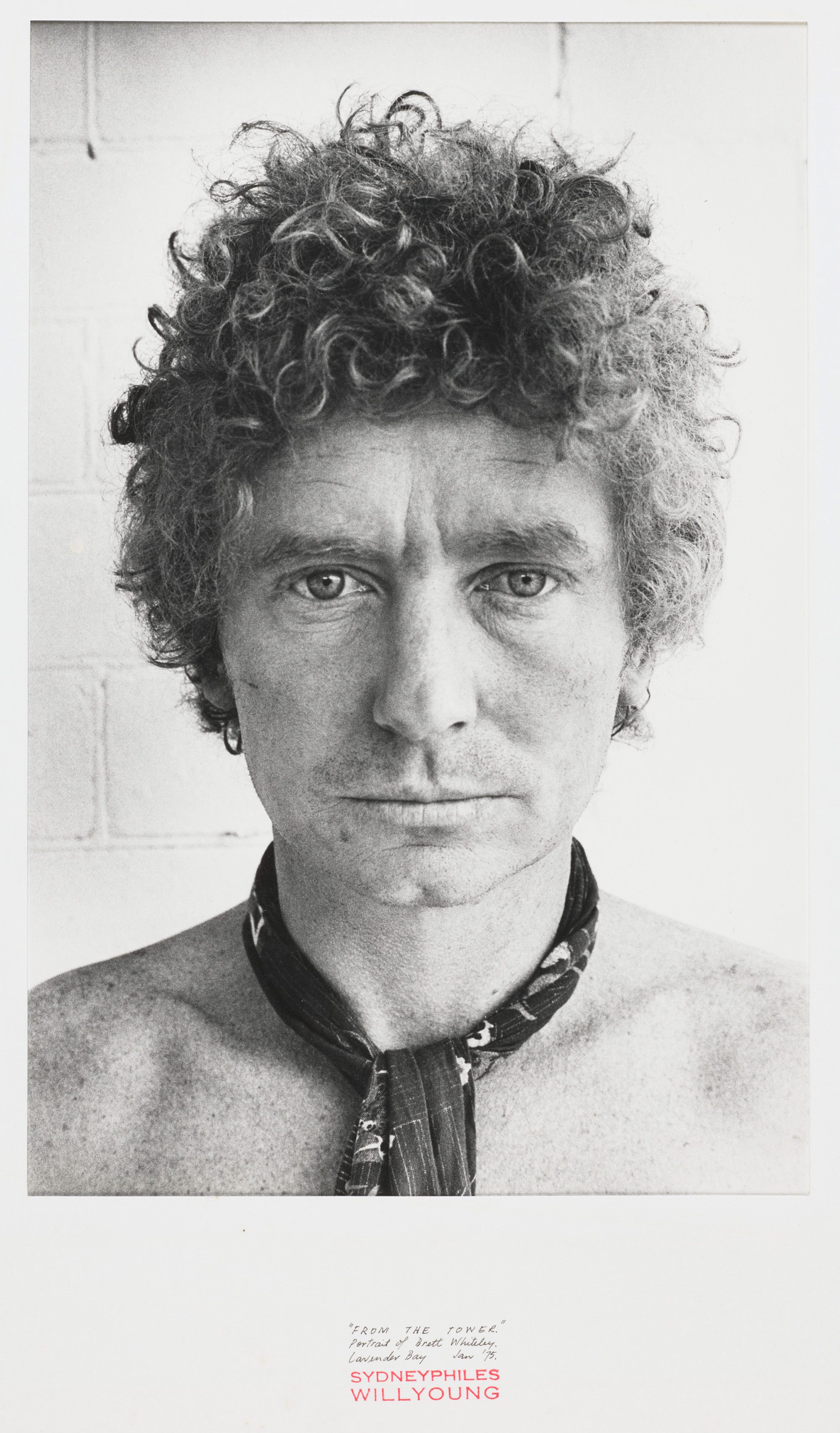 Black and white portrait of a man, shirtless, wearing a scarf tied around his neck.